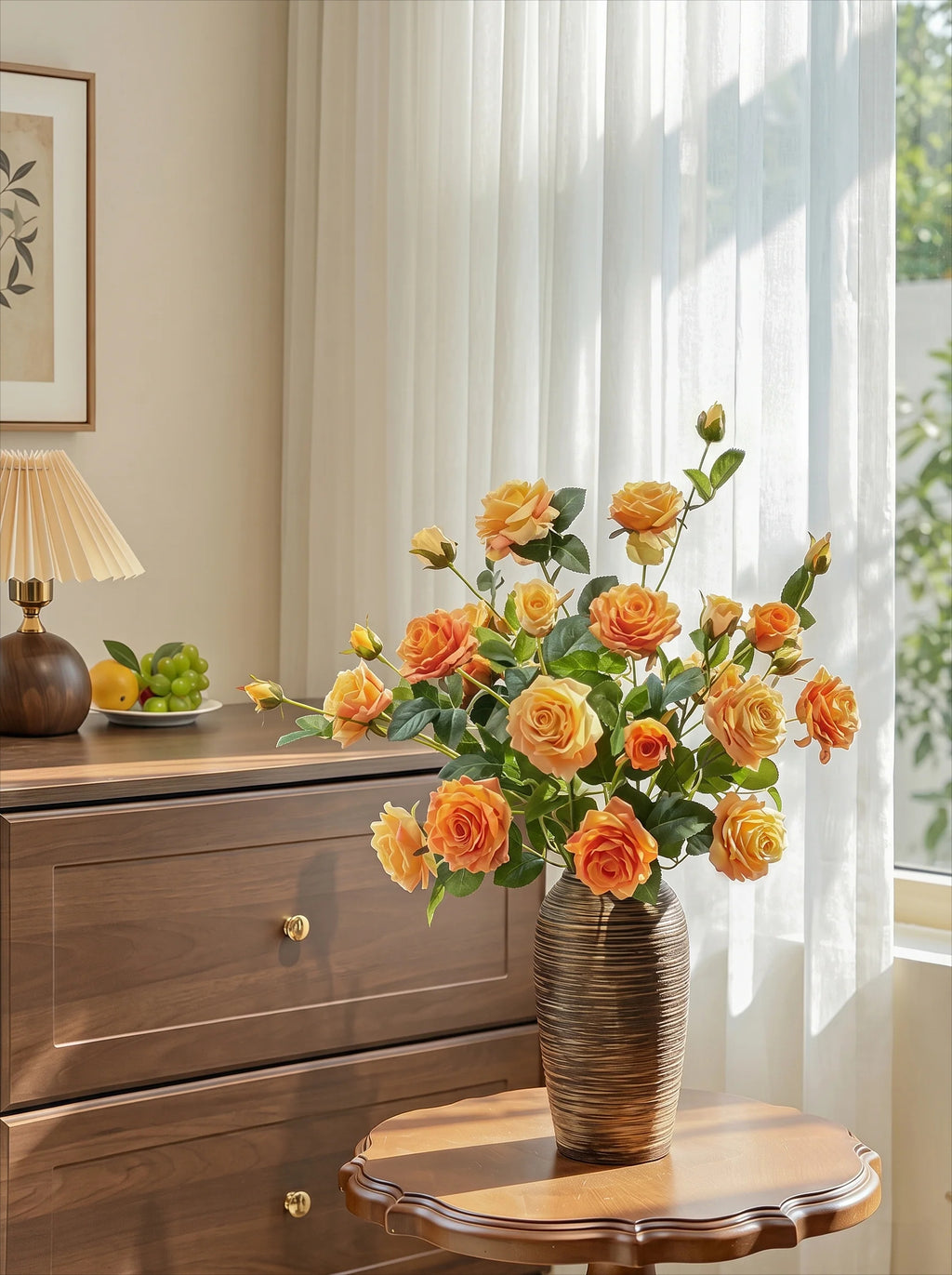 A bouquet of orange and yellow roses with green leaves arranged in a ribbed brown ceramic vase, placed on a small wooden table in a bright room with sheer white curtains, a wooden dresser, and a lamp in the background.
