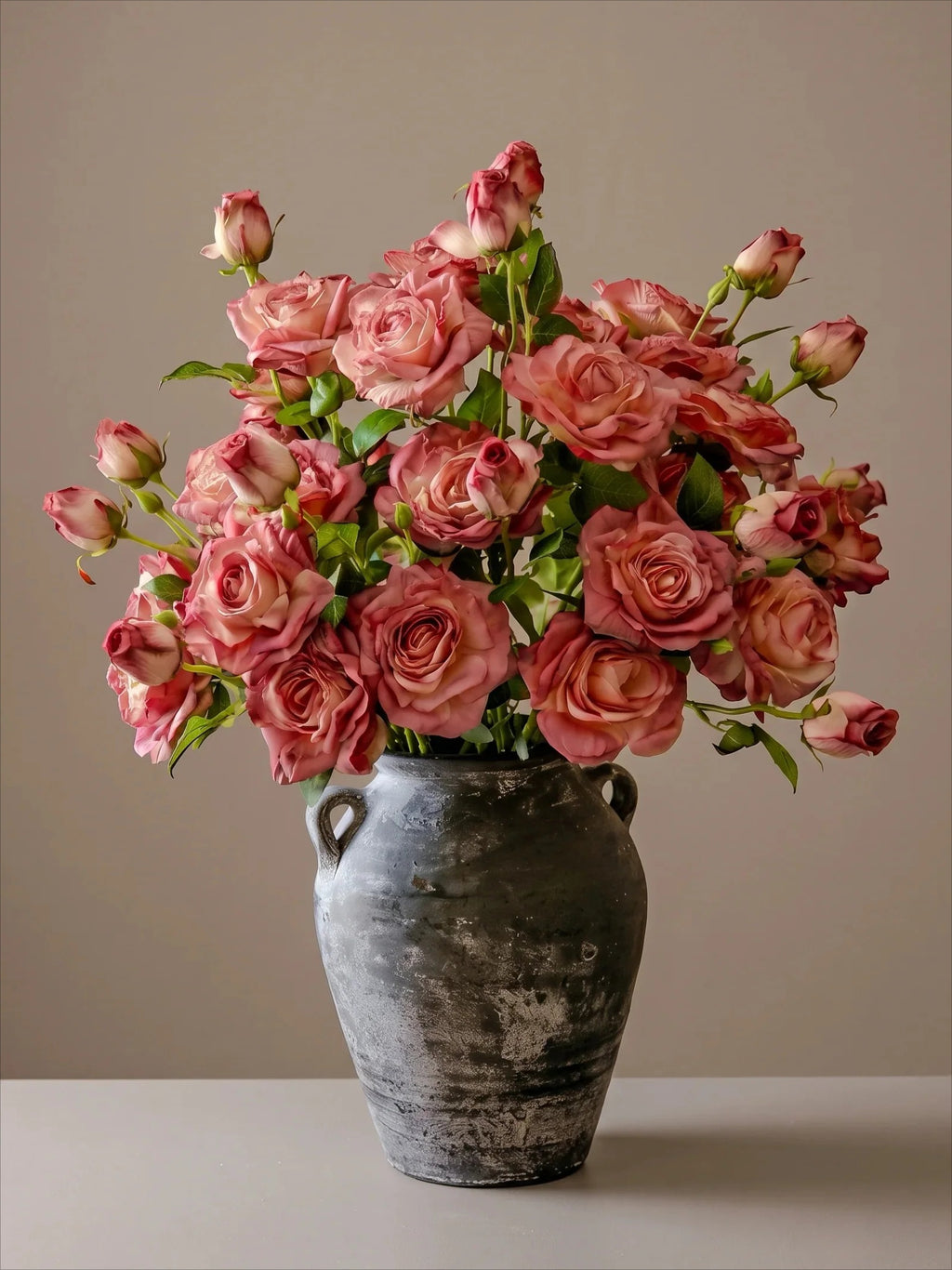 Elegant konstblommig arrangemang - rosa ros och grönska