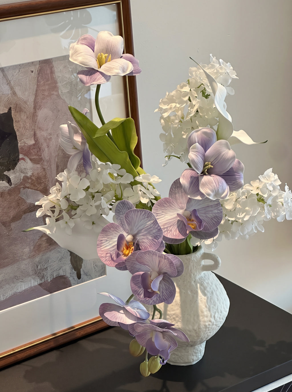 Eteriskt konstgjort blomsterarrangemang med lila orkidéer och tulpaner