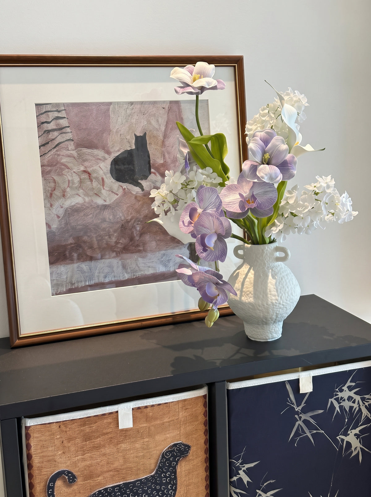 Eteriskt konstgjort blomsterarrangemang med lila orkidéer och tulpaner