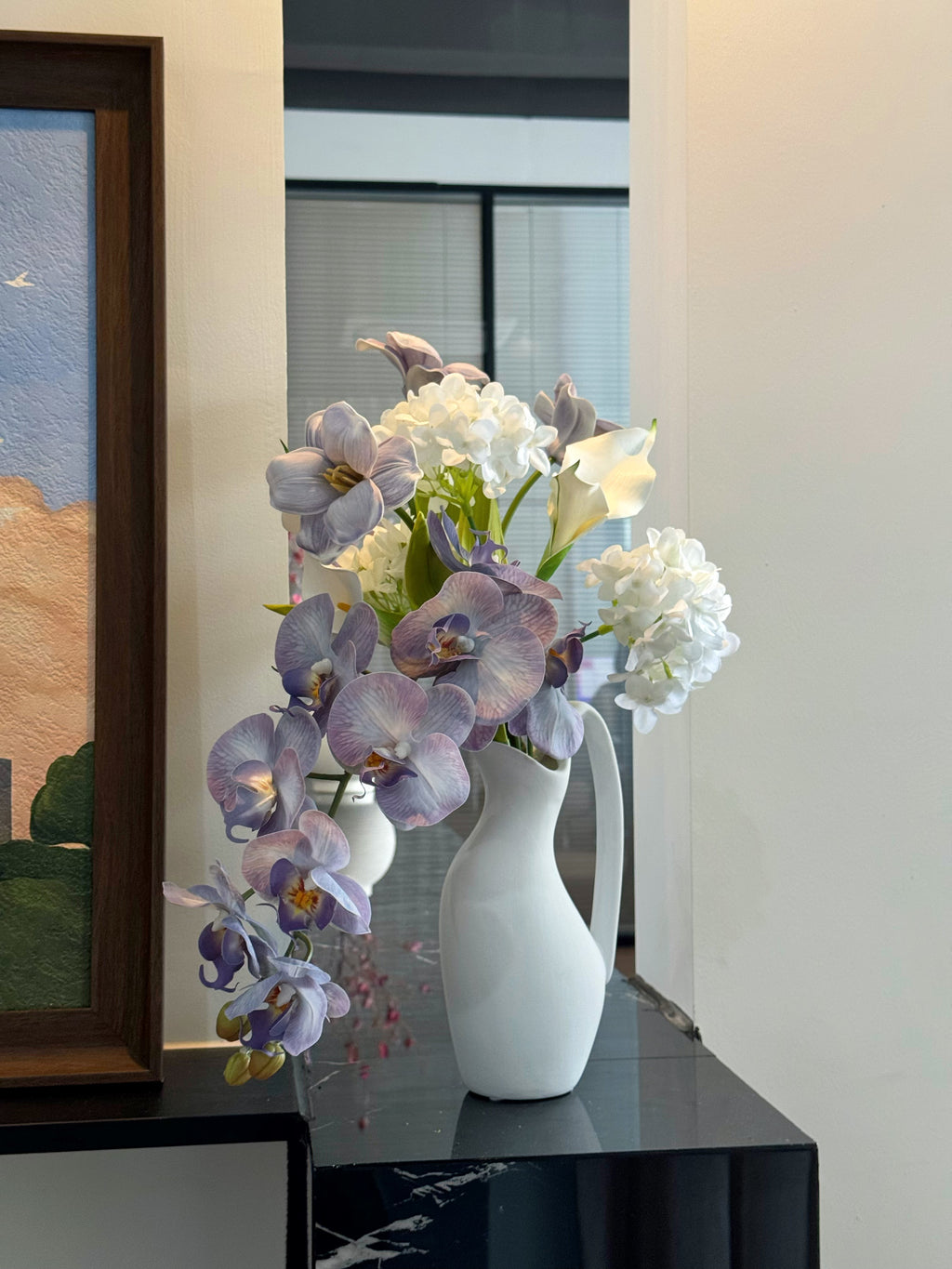 Eteriskt konstgjort blomsterarrangemang med lila orkidéer och tulpaner