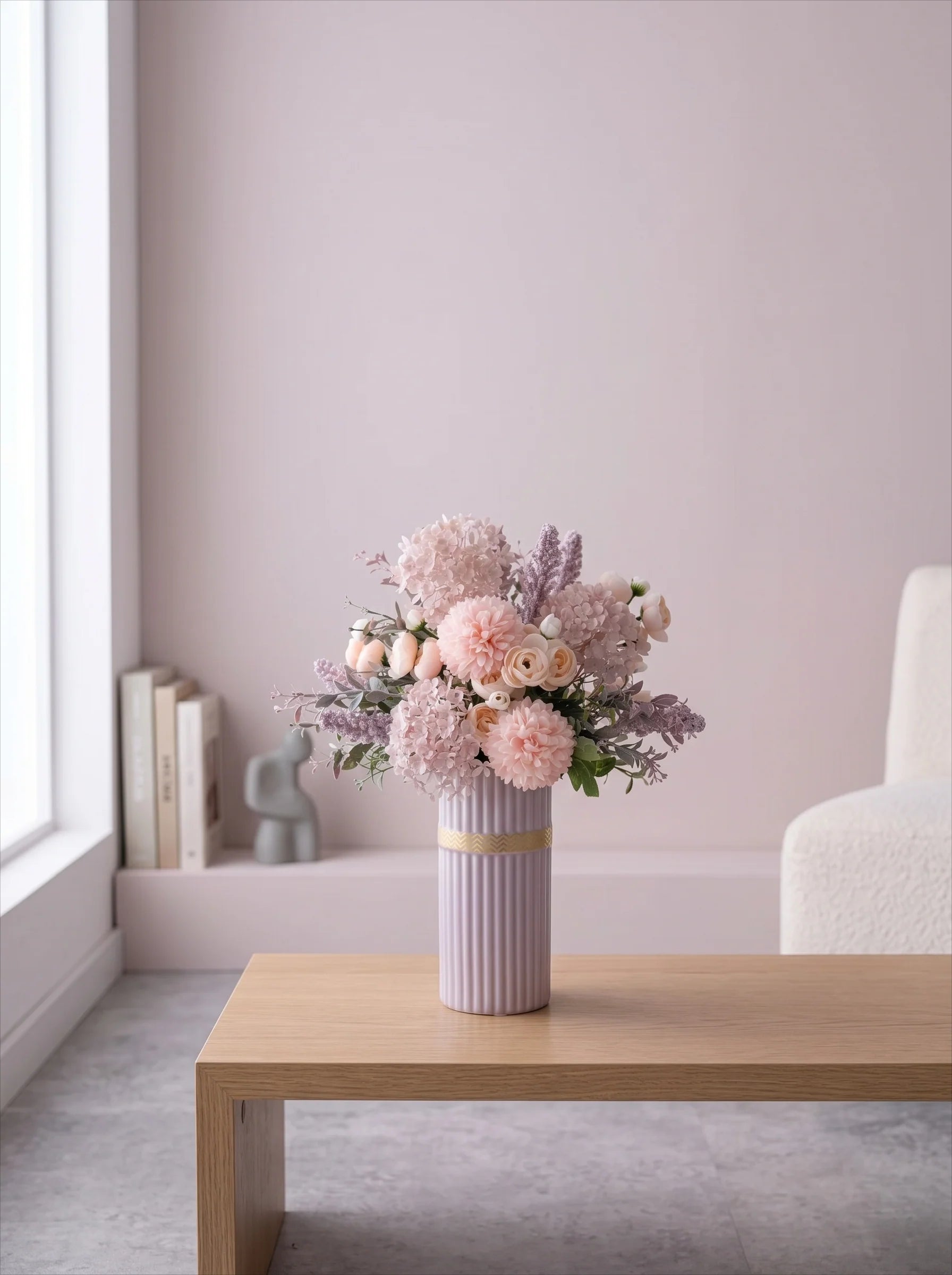 A pastel pink and lavender floral arrangement in a ribbed lavender vase with a gold band, displayed on a light wood table in a softly lit modern room.