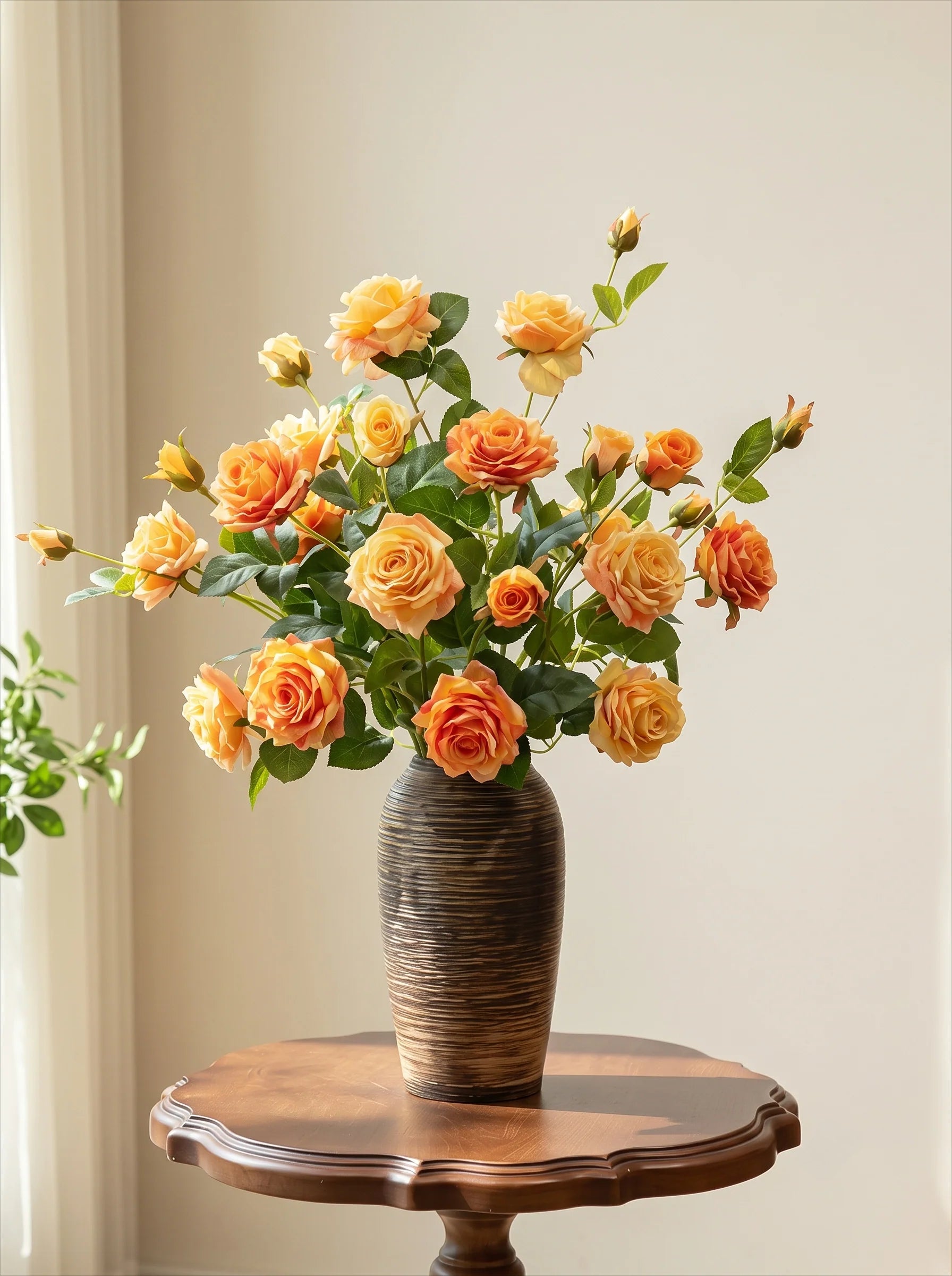 A bouquet of artificial orange and yellow roses with green leaves arranged in a ribbed brown ceramic vase, placed on a round wooden table against a light beige wall.